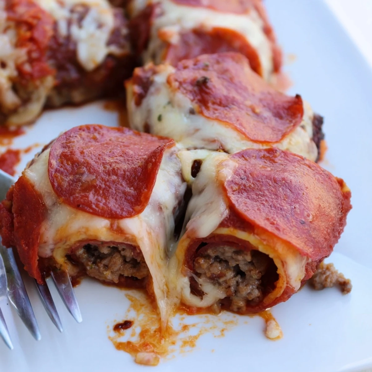 Savory low-carb beef and pepperoni roll ups baked until bubbly with parmesan cheese topping