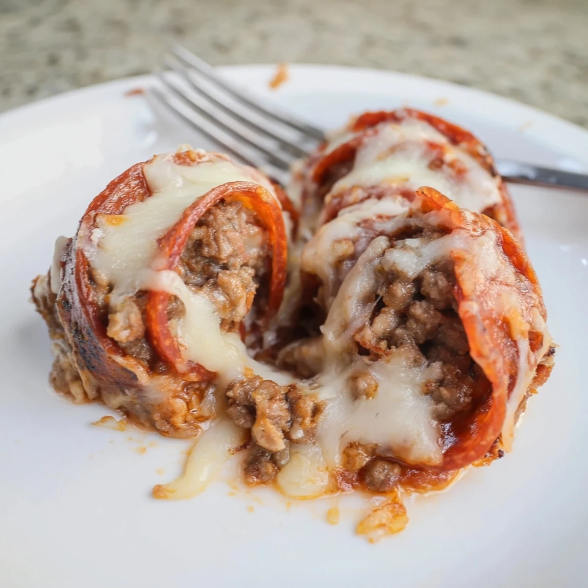 Perfectly cooked keto beef pepperoni cheese roll ups served with marinara sauce for dipping