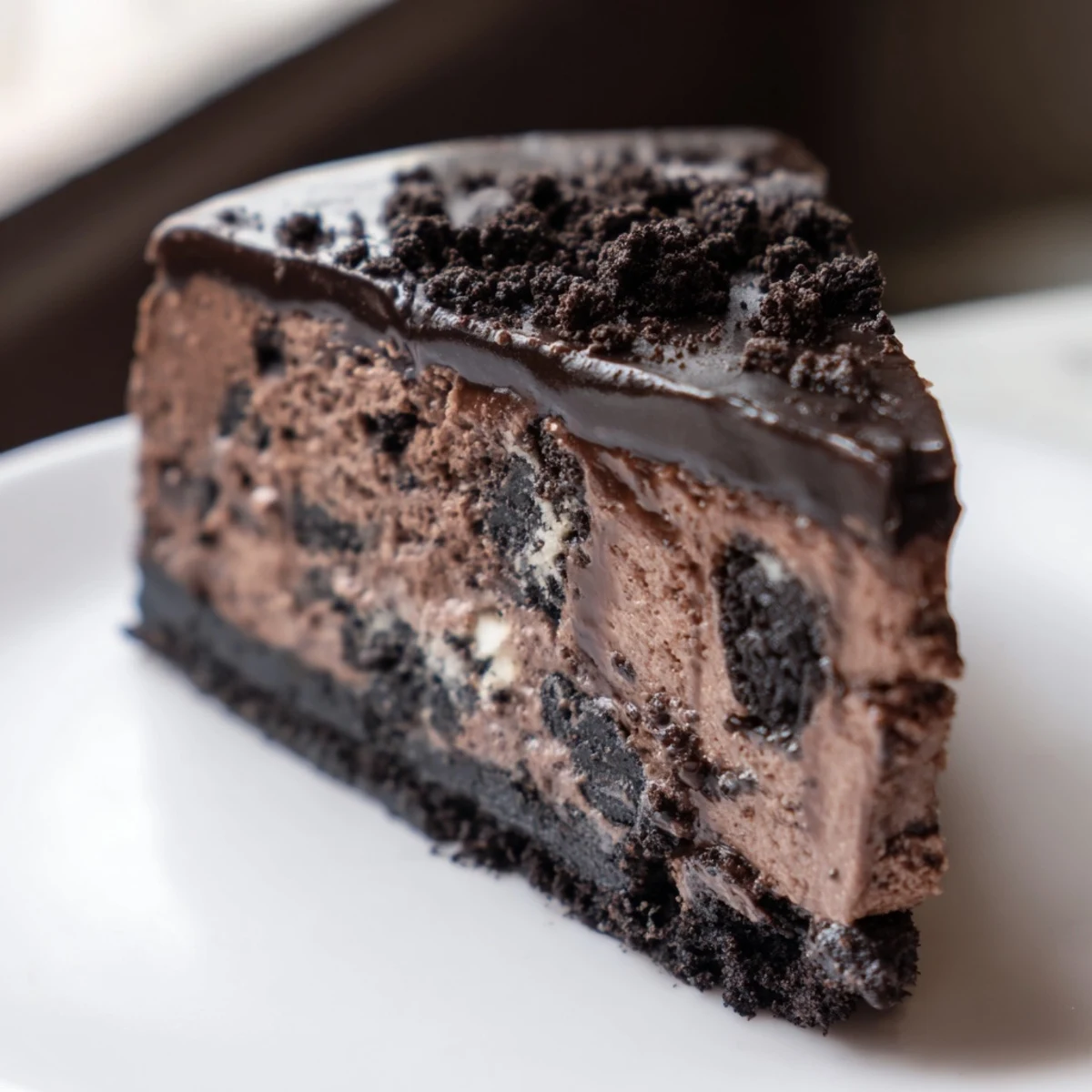 Decadent Oreo chocolate cheesecake topped with crushed cookies and a smooth chocolate glaze