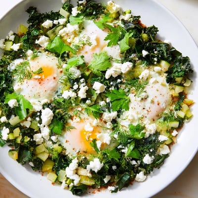 Spoonfuls of creamy feta top this fresh green shakshuka, served with warm toast for dipping.