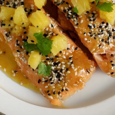 Pineapple Glazed Salmon Fillets topped with juicy pineapple chunks and green onion on a white plate, ready for a healthy dinner.
