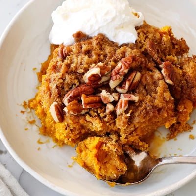 Creamy pumpkin dump cake topped with buttery pecan crumbs and served warm