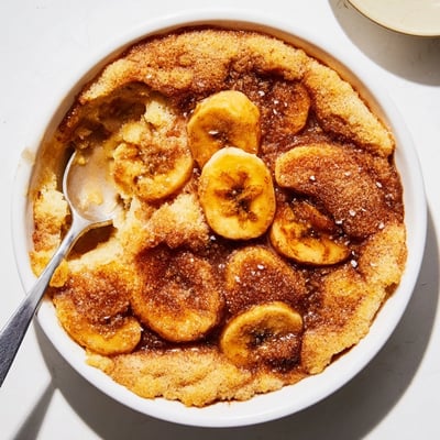 Warm Southern banana cobbler served in a dish with melted vanilla ice cream
