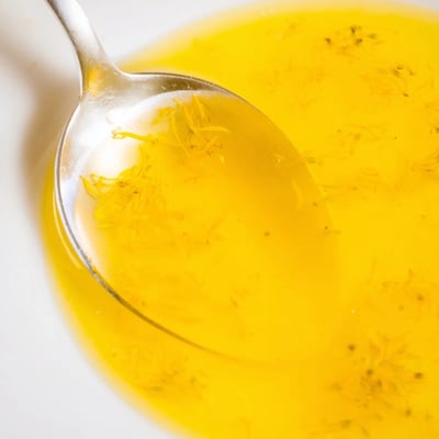 Translucent homemade fresh dandelion jelly glistening in a half-pint jar