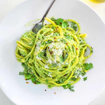 Vibrant green goddess pasta sauce blended with fresh basil and avocado served steaming hot