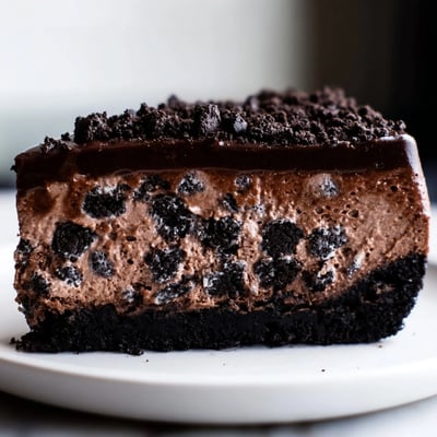 Rich Oreo chocolate cheesecake with a cookie crust drizzled in warm chocolate ganache